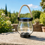 Solar flame lantern charging in bright daylight on a stone garden table, solar panel catching the sun